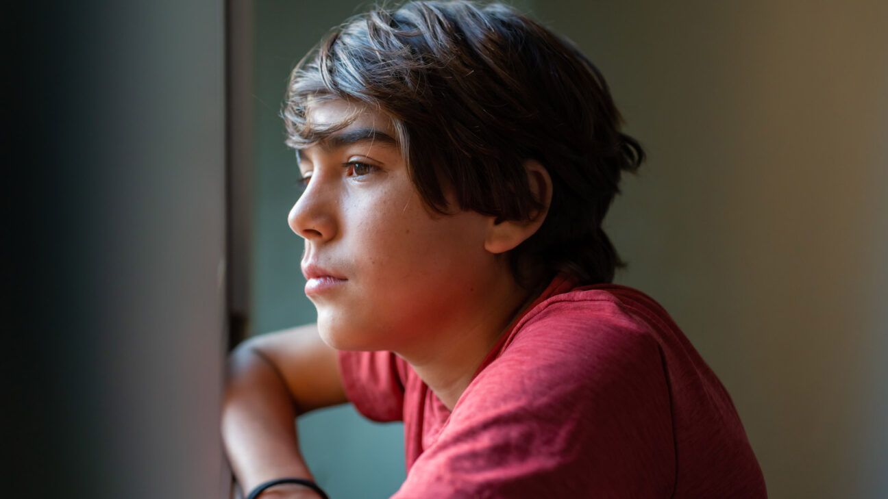 Teenager looking out a window.