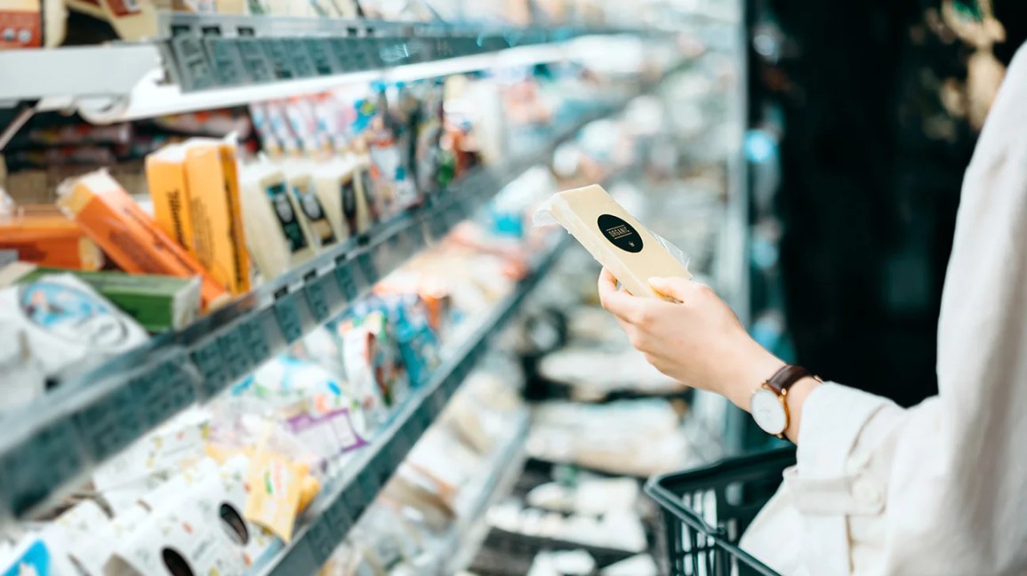 examining package of cheese in supermarket
