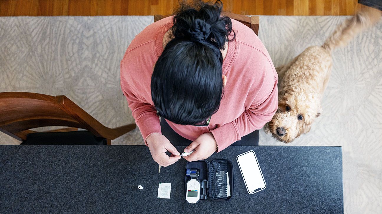 Female checks glucose monitor on table