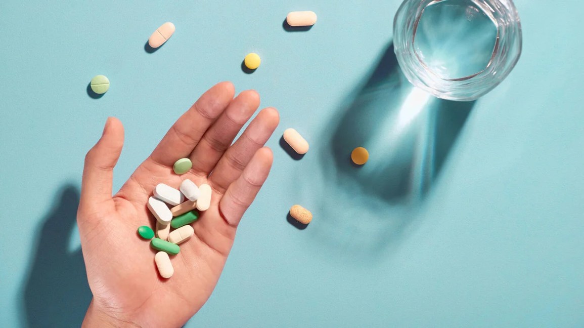 pills in hand with a glass of water